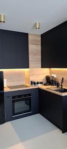 a kitchen with black cabinets and a sink at Apartament ROYAL in Koszalin