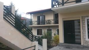 a white house with a black door and stairs at STYGA APARTMENTS in Kalavrita