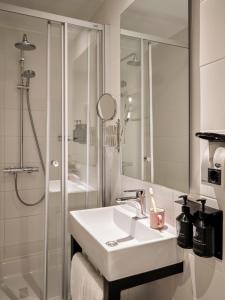 a white bathroom with a sink and a shower at Max Brown Hotel Museum Square, part of Sircle Collection in Amsterdam