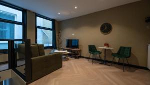 sala de estar con sillas verdes y reloj en la pared en Downtown Suite en La Haya