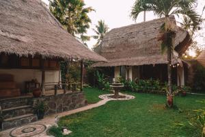 una casa con techo de paja y patio en Sasak Experience, en Kuta Lombok