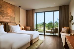 a hotel room with two beds and a balcony at Mövenpick Resort Waverly Phu Quoc in Phu Quoc