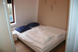 ein kleines Bett mit zwei blauen Kissen in einem Zimmer in der Unterkunft Liguster 59* in Nieuwvliet