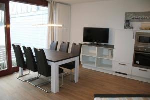 ein Esszimmer mit einem Tisch mit Stühlen und einem Fernseher in der Unterkunft Liguster 59* in Nieuwvliet