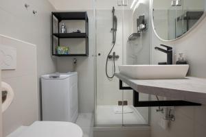 ein Badezimmer mit einem Waschbecken, einem WC und einem Spiegel in der Unterkunft Bright and cozy studio with a city view in Wien