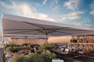 a large white umbrella on a patio with tables and chairs at Palazzo Cordusio, a Gran Melia Hotel in Milan