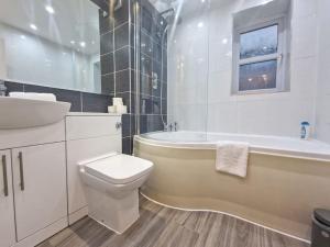 a bathroom with a tub and a toilet and a sink at Free Parking: Perfect City Centre Flat in Manchester