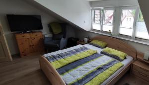 1 dormitorio con 1 cama, TV y silla en Ferienwohnung Familie Süttner, en Nagel