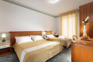 a hotel room with two beds and a table at Hotel Zeus in Cesenatico