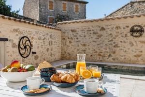 a table with breakfast foods and orange juice on a balcony at Le Patio d'Arlou & Spa - Relaxant et romantique in Fabrezan