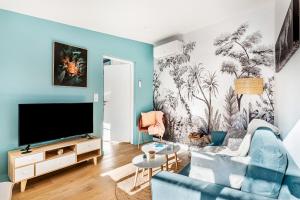 sala de estar con sofá azul y TV en Le Patio d'Arlou & Spa - Relaxant et romantique, en Fabrezan