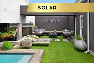 a patio with a pool and green grass at Le Petit Bijou Boutique Apartments - Solar Power in Franschhoek
