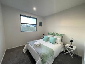 a bedroom with a large bed with a window at Luxury Brand New 4 Bedroom Family Retreat in Christchurch
