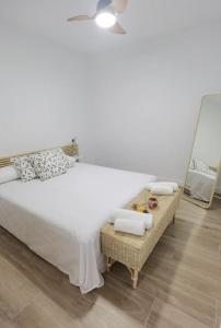 Un dormitorio con una cama blanca y un espejo. en Fantástico piso nuevo, Mentidero, en Cádiz