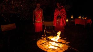 two women standing next to a fire in the dark at Soroi Mara Bush Camp in Masai Mara