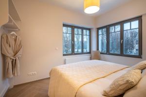 een slaapkamer met een bed in een kamer met ramen bij Villa Come in Luxemburg