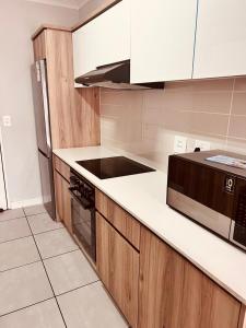 a kitchen with white counter tops and wooden cabinets at The Blyde in Pretoria