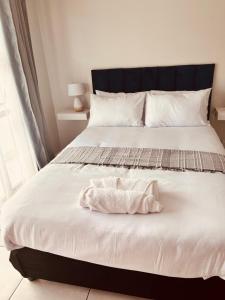 a bedroom with a white bed with a black headboard at The Blyde in Pretoria