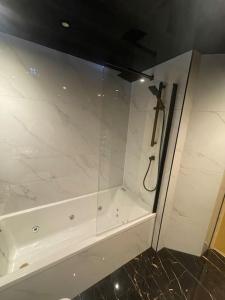 a white bathroom with a glass wall with a scissors at 2bedroom apartment/steam room in Carnoustie