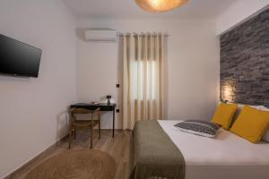 1 dormitorio con cama con almohadas amarillas y escritorio en Casa 28 City Apartments, en La Canea