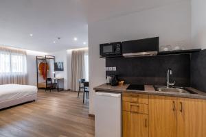Una cocina con fregadero y una cama en una habitación. en Pnoe Urban Living, en Atenas