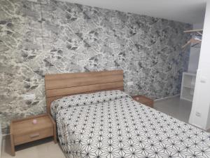 - une chambre avec un lit et un mur en pierre dans l'établissement Apartamento independiente en plena naturaleza Vallromanes Barcelona, à Vallromanas