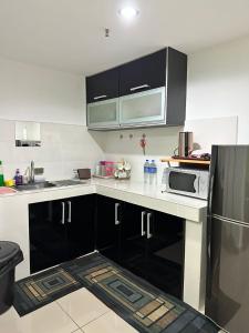 a kitchen with black and white cabinets and a refrigerator at Devianna Al Fateh Wakaf Che Yeh in Kota Bharu