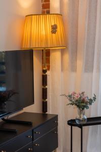 een televisie en een lamp op een tafel met een vaas met bloemen bij Warsaw Pruszków Park View Comfortable Apartments by Renters in Pruszków