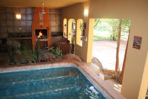 a swimming pool in a house with a fireplace at Kiburi Lodge @ Kruger, a secluded Bushveld getaway in Marloth Park