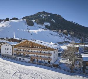 ein Gebäude im Schnee vor einem Berg in der Unterkunft Hotel Hubertushof in Saalbach-Hinterglemm