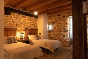 2 camas en una habitación con una pared de piedra en Arialdegi en San Marcos