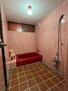 a pink tiled bathroom with a red bath tub at ロビンホテルRobin Hotel in Yachimata