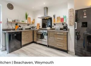 uma cozinha com armários de madeira e um forno com placa de fogão em Beachaven (7 Bedroom/5 Bathroom) em Weymouth