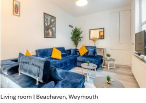 a living room with a blue couch and yellow pillows at Beachaven (7 Bedroom/5 Bathroom) in Weymouth