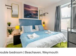 a bedroom with a blue bed with two towels on it at Beachaven (7 Bedroom/5 Bathroom) in Weymouth