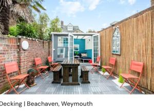 um pátio com cadeiras vermelhas, uma mesa e uma cerca em Beachaven (7 Bedroom/5 Bathroom) em Weymouth