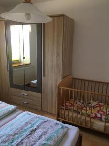 een slaapkamer met een wieg en een grote spiegel bij Fewo Claudia - ABC332 in Neuburg