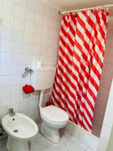 baño con aseo y cortina de ducha roja y blanca en Beach Tree House en Cortegaça