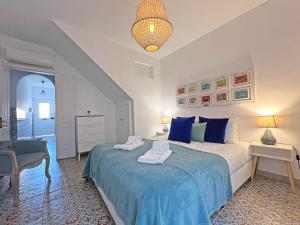 Schlafzimmer mit einem Bett mit blauer Bettwäsche und einem Stuhl in der Unterkunft Casa Figueiras - Tavira in Tavira