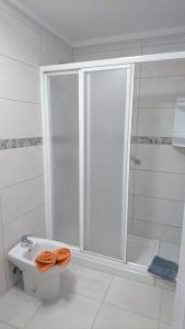 プエルト・デ・サンティアゴにあるArenasの白いバスルーム(シャワー、トイレ、オレンジタオル付)