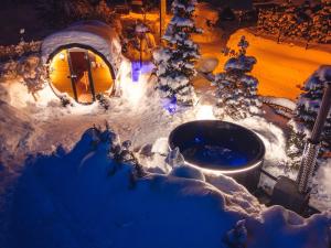 una bañera de hidromasaje al aire libre en la nieve por la noche en GORSKI RESORT Lux Apartments Jacuzzi & Sauna, en Poronin