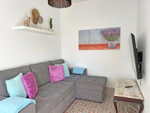 ein Wohnzimmer mit einer grauen Couch mit rosa und blauen Kissen in der Unterkunft Casa Figueiras - Tavira in Tavira