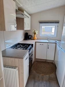 a small kitchen with a stove and a sink at EnJoy Meer und See Ferienhaus -Aan het Lauwersmeer in Lauwersoog -3 Slaapkamers - 1 tot 6 pers -Vanaf 14u al inchecken! Free WIFI! in Lauwersoog