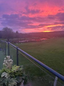 een zonsondergang boven een groen veld met een hek bij Celtic Minor Cottage in Ystalyfera