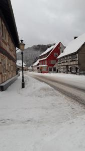 a snow covered street with buildings and a light pole at Mittel-Schänke Wieda in Walkenried