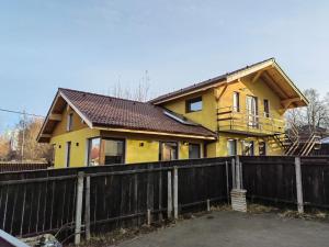 una casa amarilla con una valla delante de ella en Jegenye apartments en Miercurea-Ciuc