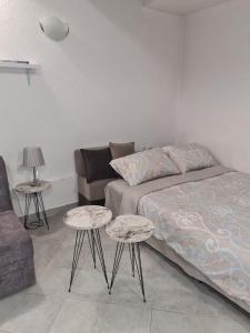 un soggiorno con un letto e due tavoli di Apartman Sofija Kraljevo a Kraljevo