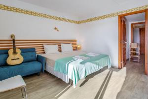 ein Schlafzimmer mit einem Bett und einem blauen Sofa und einer Gitarre in der Unterkunft Lovely Apart with Balcony - Beach FL by LovelyStay in Cabanas de Tavira