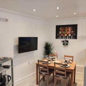 a dining room with a table and a television on a wall at Stunning 2-Bed Apartment in London Dagenham in Dagenham