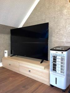 a flat screen tv sitting on top of a wooden entertainment center at Charming 1-Bed loft Apartment in Romford in Romford